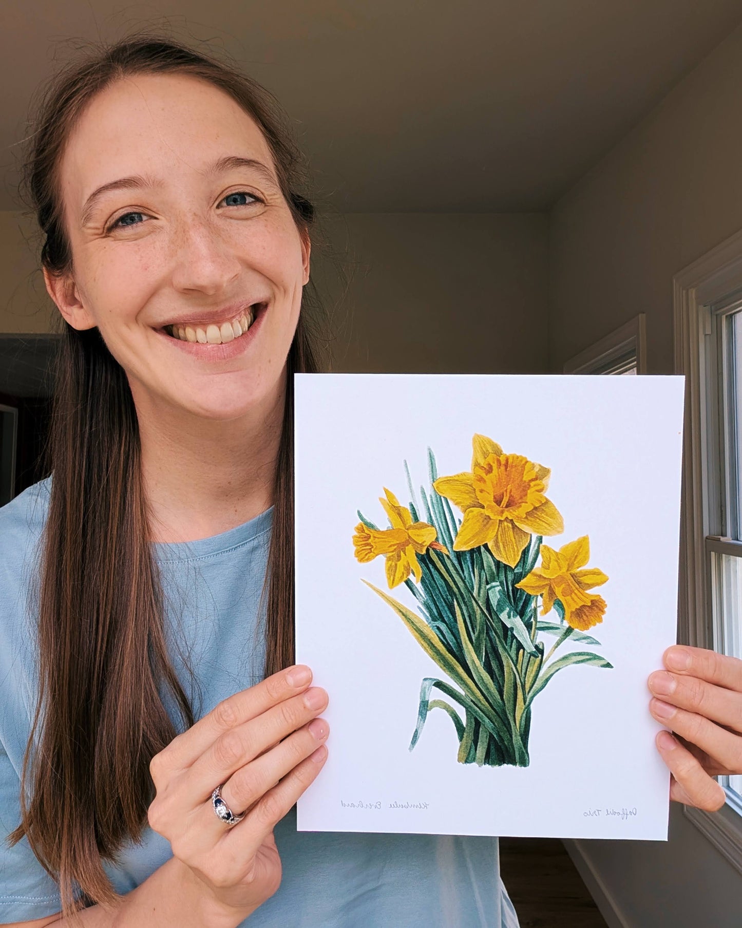 Person holding a print of yellow flowers indoors