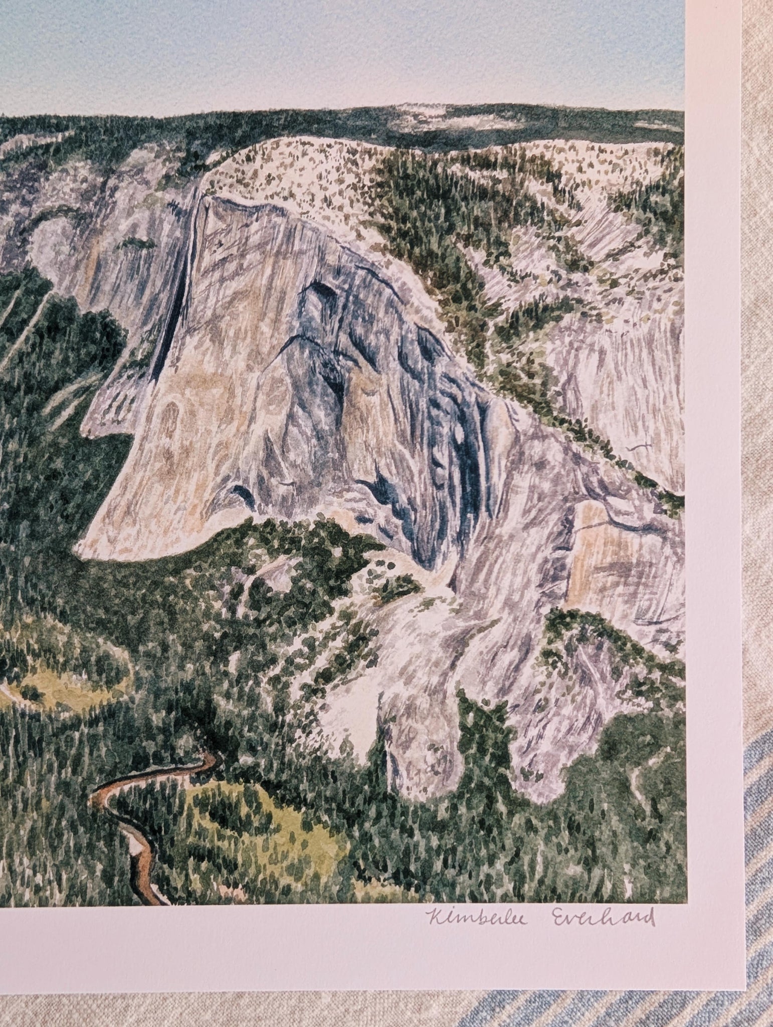 Aerial view of a mountain landscape with a winding road and forested areas.