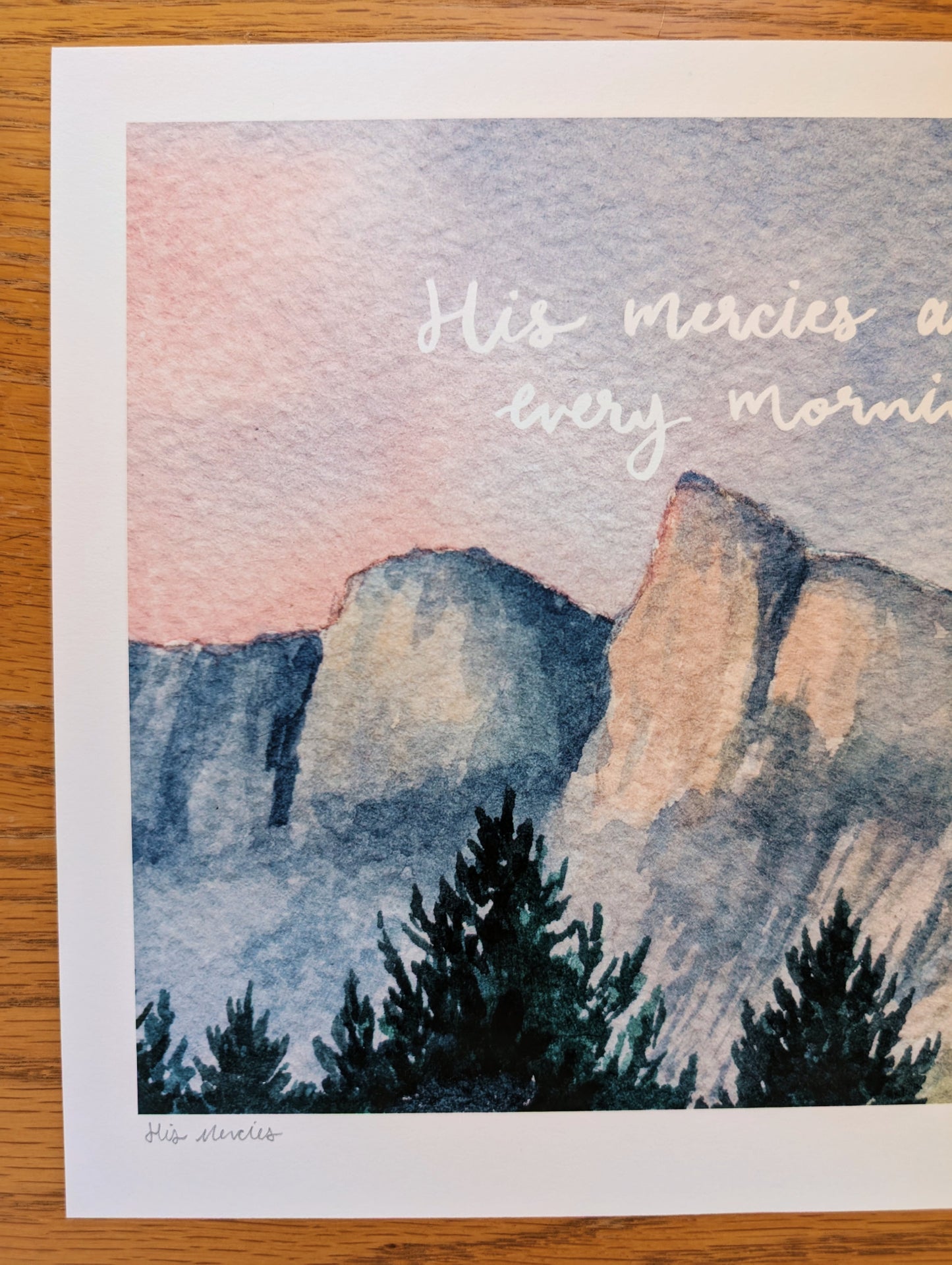 Mountain landscape with trees and 'His mercies are every morning' text on a watercolor background.
